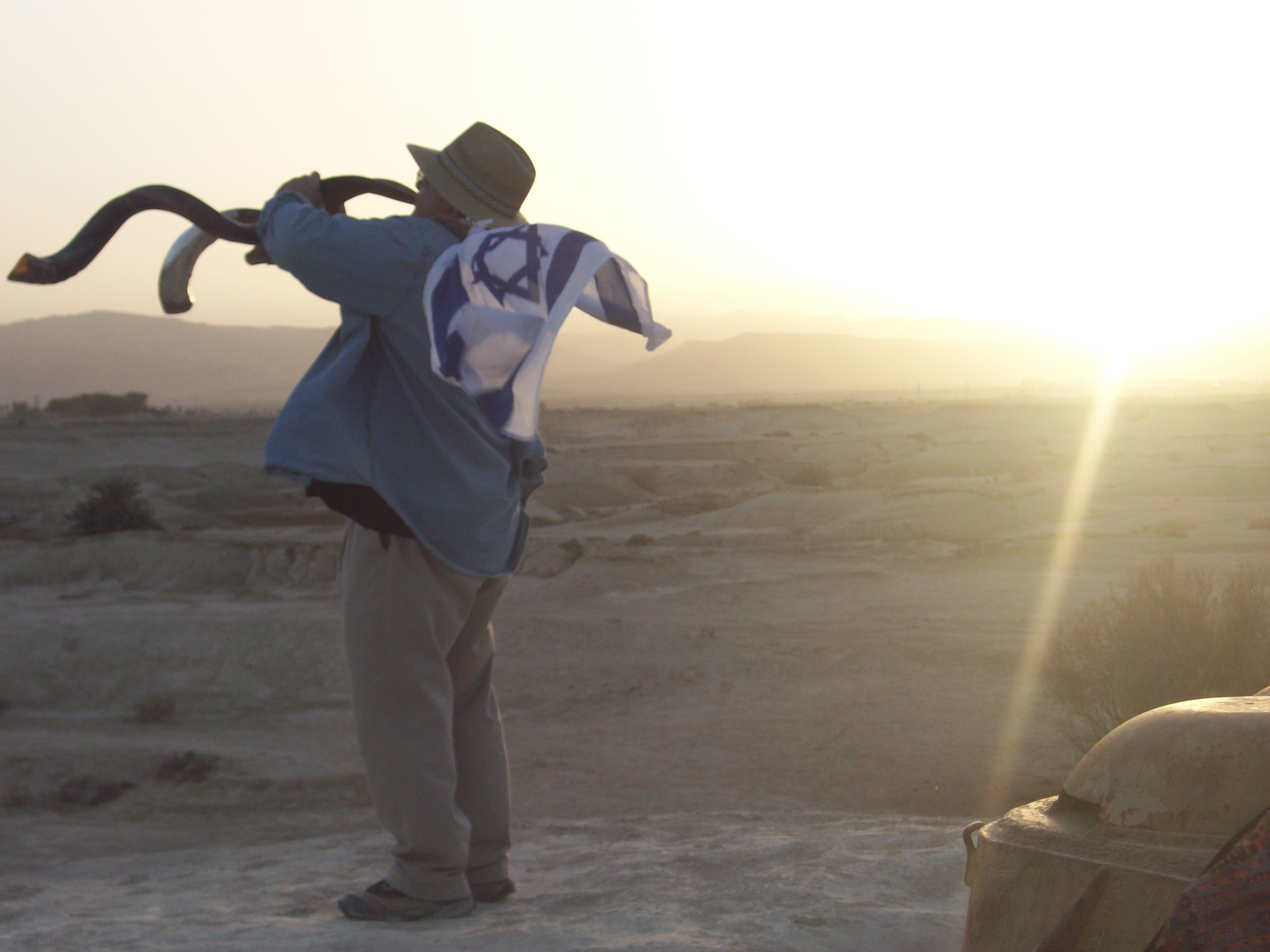 Robert Weinger sounding the shofar across the desert at sunset, the Israeli flag over his shoulders — from Mt. Diablo to the Promised Land